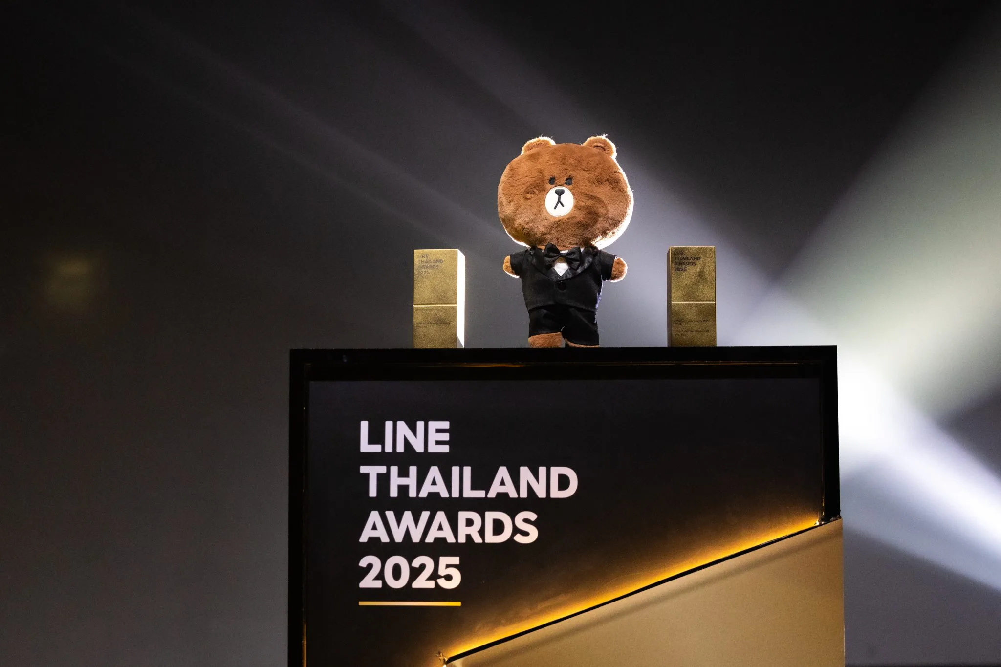 Branded ceremony desk and mascot on stage.
